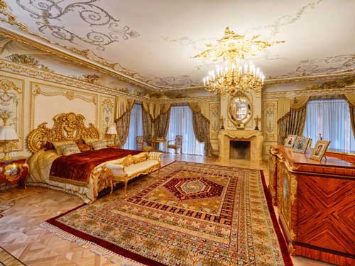 A grand bedroom with a large red and gold Persian rug