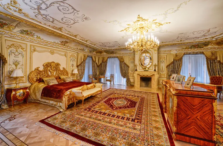 A red and gold Persian rug in an ornate bedroom