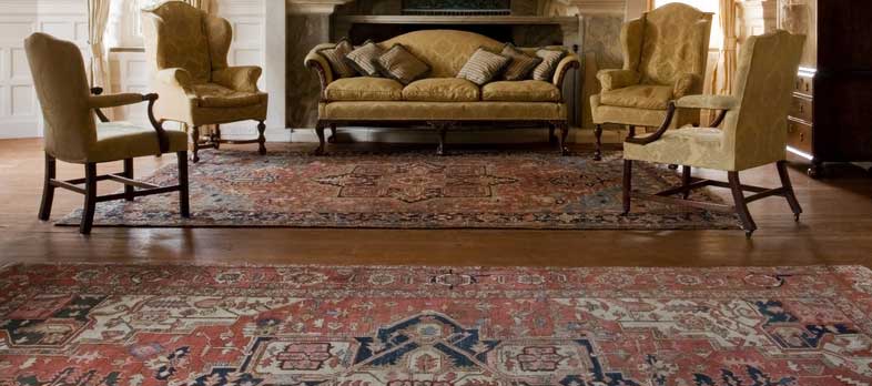 A large patterned oriental rug in an elegant sitting room with a fireplace
