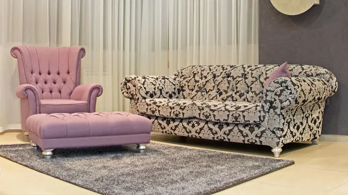 A pink armchair and a patterned sofa in a bright living room