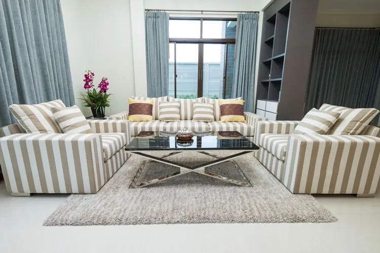 A grey synthetic rug between striped sofas