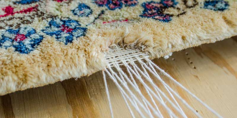 Close-up of the end of a rug, where the fringe threads come out of the pile