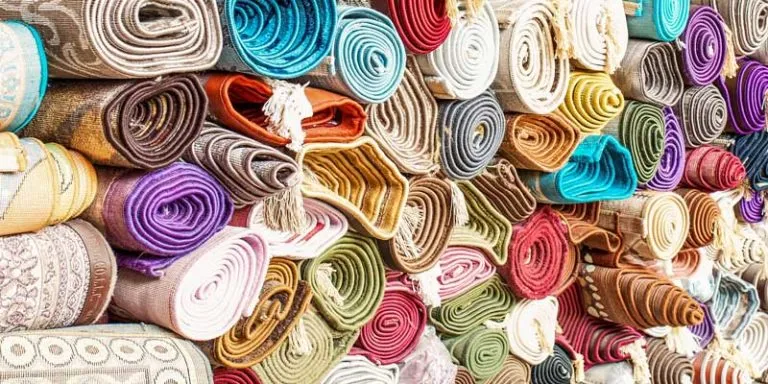 Rolled-up flat-woven rugs in many bright colours