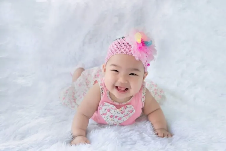 A smiling baby on a fluffy white shag rug